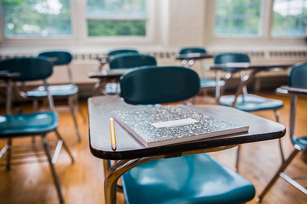 a notebook and pencil on a desk in a school classroom
